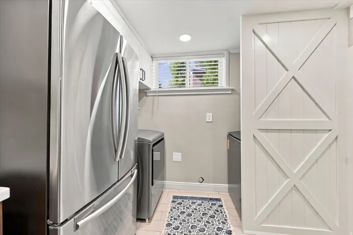 Laundry area featuring a side-by-side washer and dryer, stainless steel refrigerator, white shaker-style cabinetry, a window with white blinds, and recessed lighting