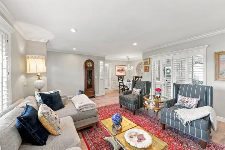 Recessed lighting, crown molding, plantation shutters, wood-finish flooring, and a decorative chandelier