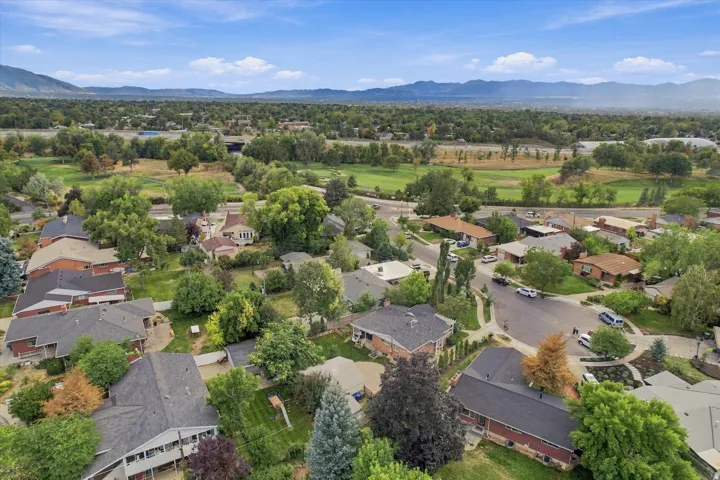 Residential neighborhood featuring mature trees, paved streets, and distant mountain scenery