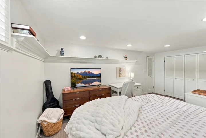Recessed lighting, built-in shelving, wood-finish flooring, white paneled closet doors, and a white desk area