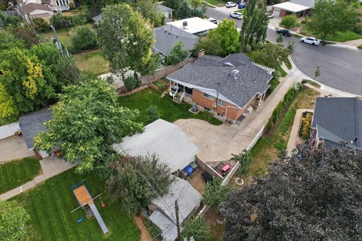 Brick exterior residence with a dark shingle roof, concrete driveway, and a fenced backyard