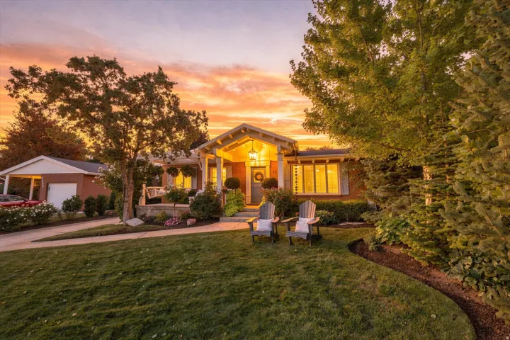 Brick exterior home with a gabled portico entrance, expansive front lawn, and mature landscaping