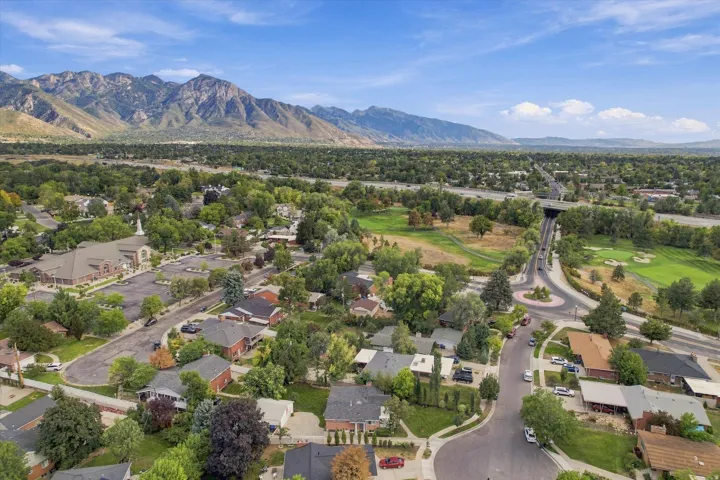 Residential neighborhood with mountain backdrop, mature trees, and a golf course