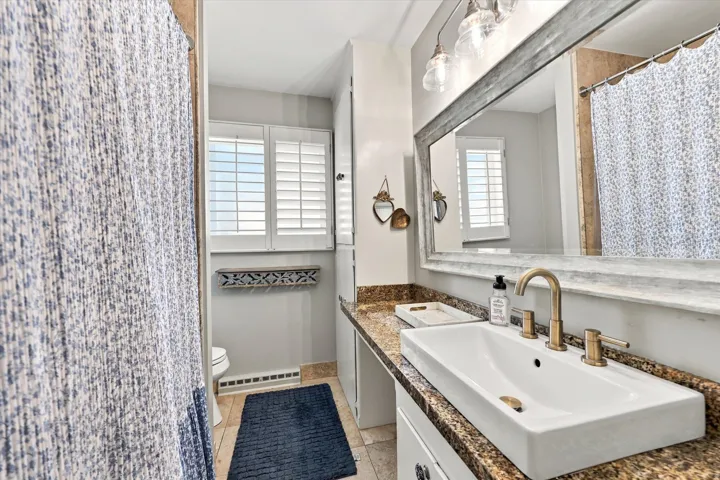 Vanity with an integrated rectangular sink, bronze-finish faucet, and a stone-finish countertop