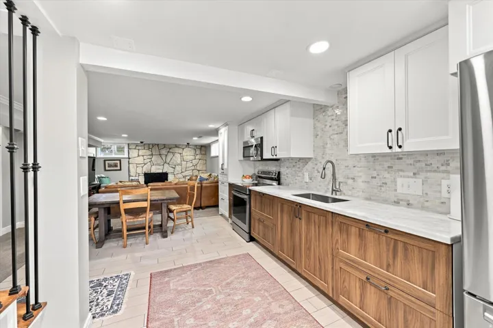 Kitchenette featuring wood-finish lower cabinetry, white upper cabinetry, and a patterned tile backsplash