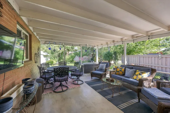 Covered patio with a concrete surface, exposed beam ceiling, and brick exterior wall