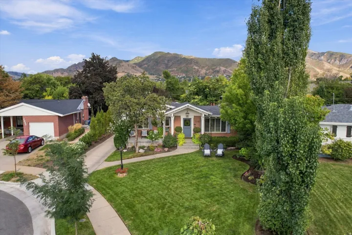 Brick exterior with a covered porch, established landscaping, and a manicured lawn