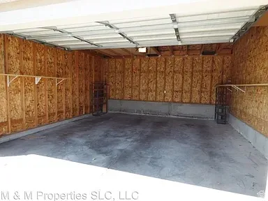 Attached garage with concrete flooring, unfinished wood paneling, and an overhead door