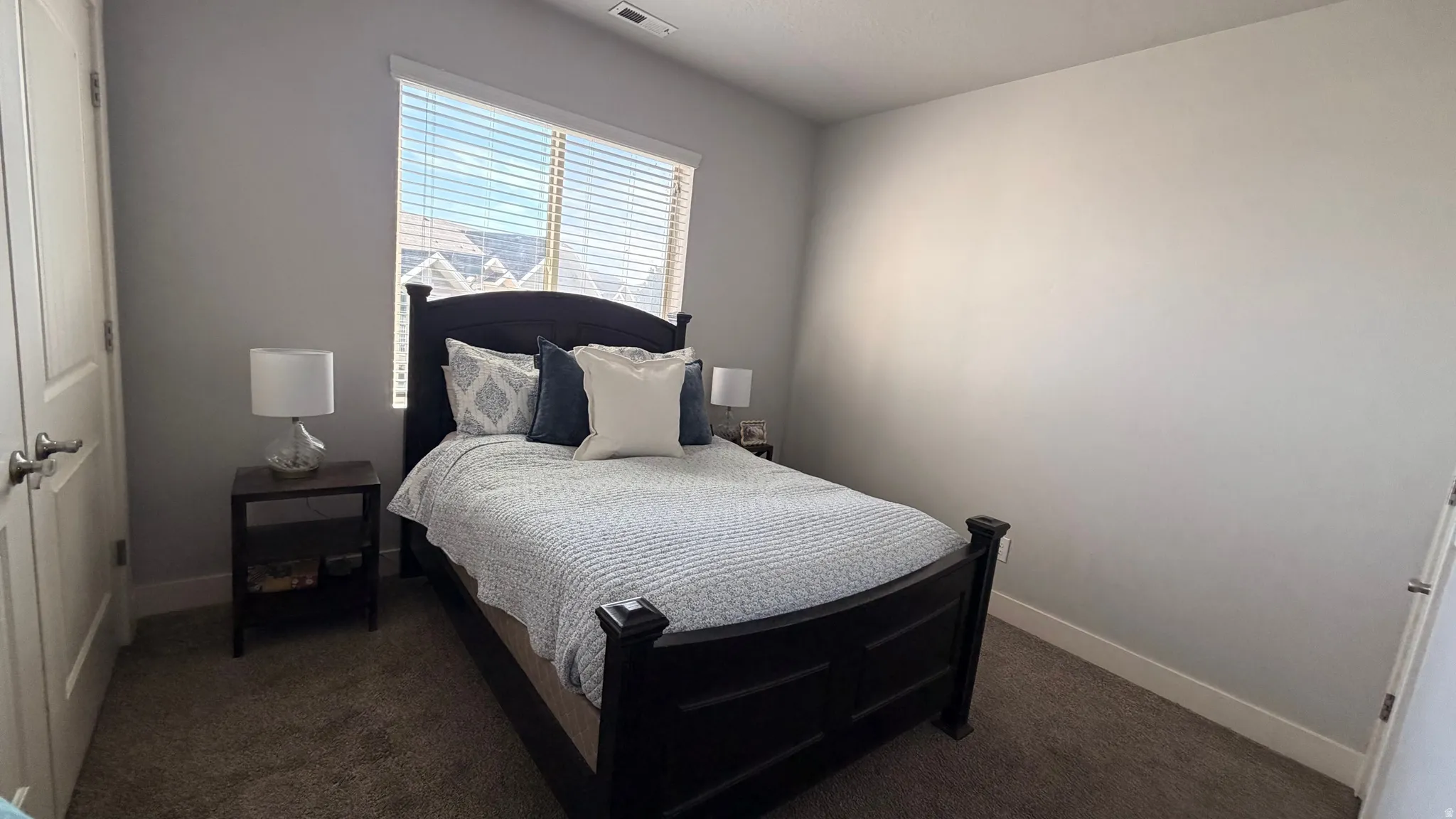 Carpeted room with a window featuring horizontal blinds, and a built-in closet with panel doors