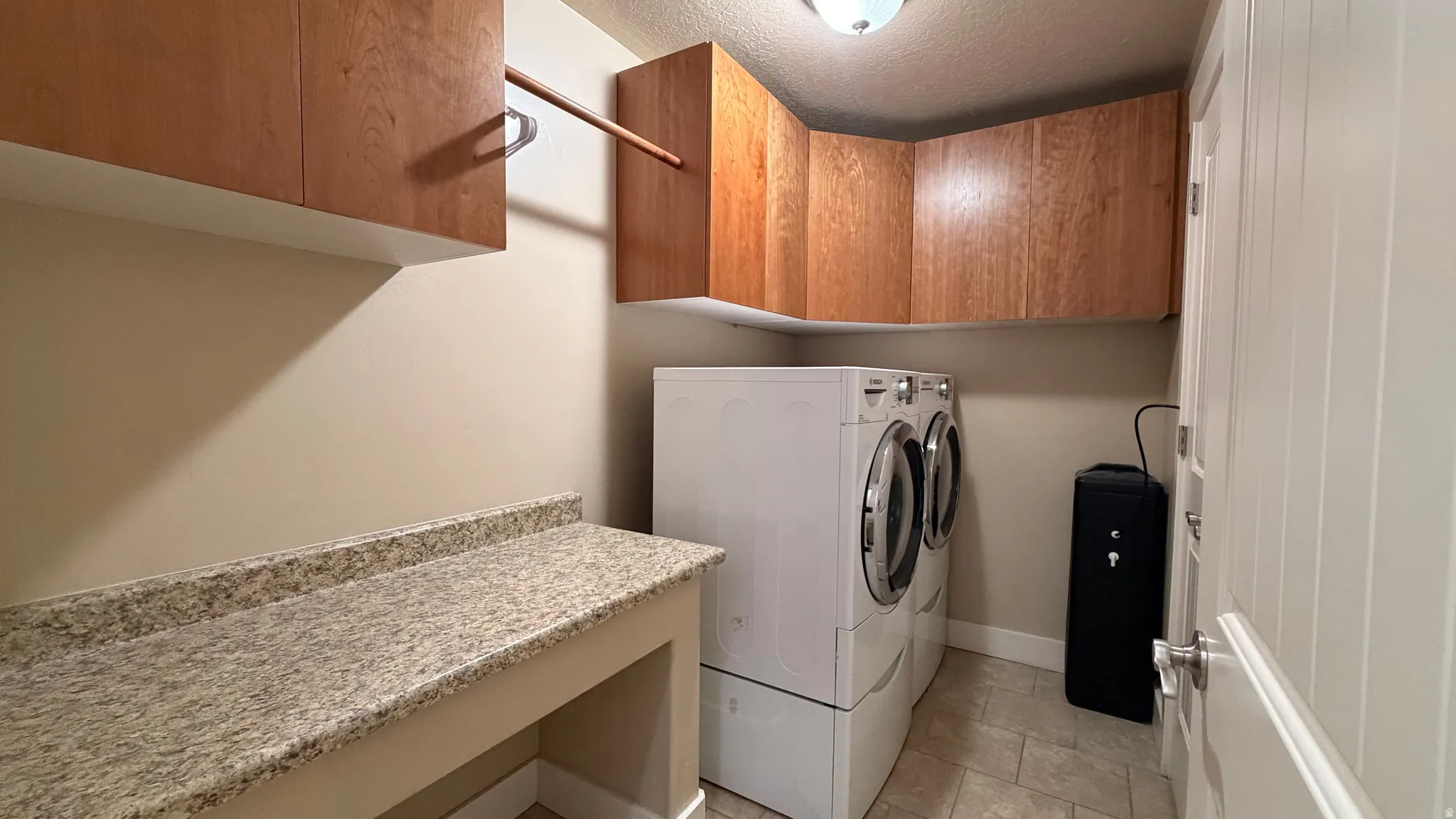 Built-in wood cabinetry, light-toned countertop, integrated hanging rod, and tiled flooring