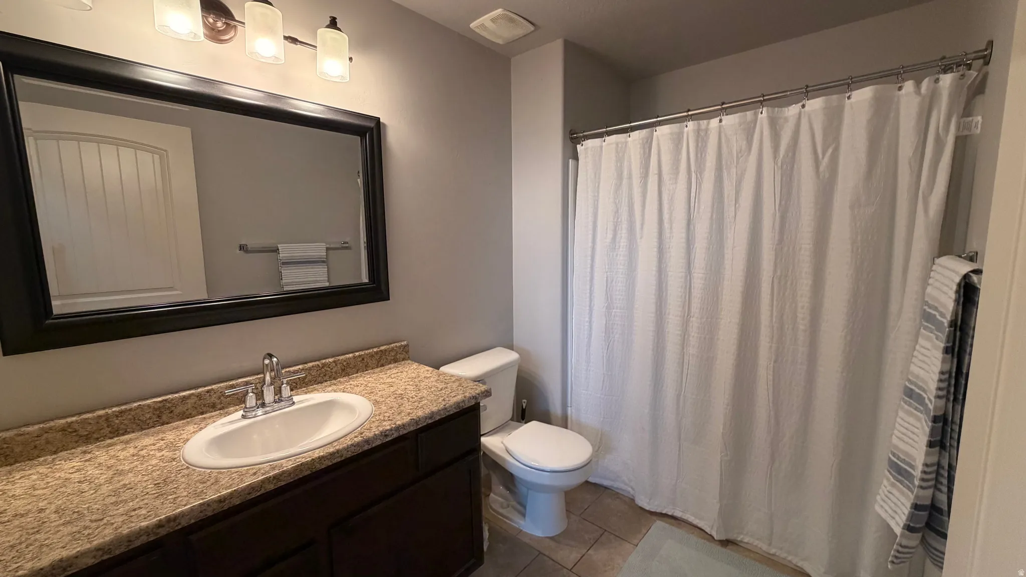 Vanity with stone-finish countertop, undermount sink, and dark wood-finish cabinetry