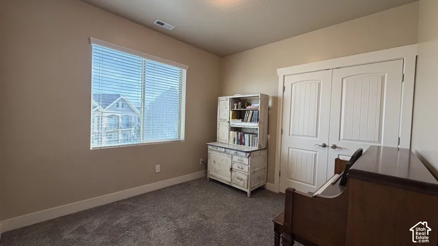 Wall-to-wall carpeting, window with horizontal blinds, and a double-door closet with paneled doors