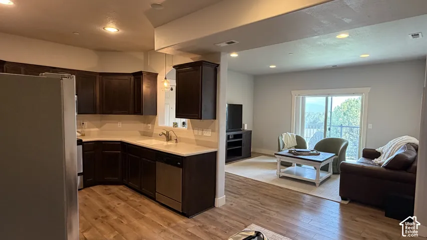 Kitchen featuring dark wood cabinetry, light countertops, and stainless steel appliances