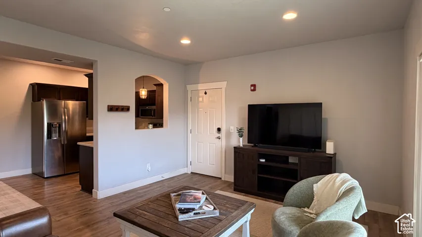 Recessed ceiling lighting, wood-finish flooring, white trim, arched pass-through window, and stainless steel refrigerator