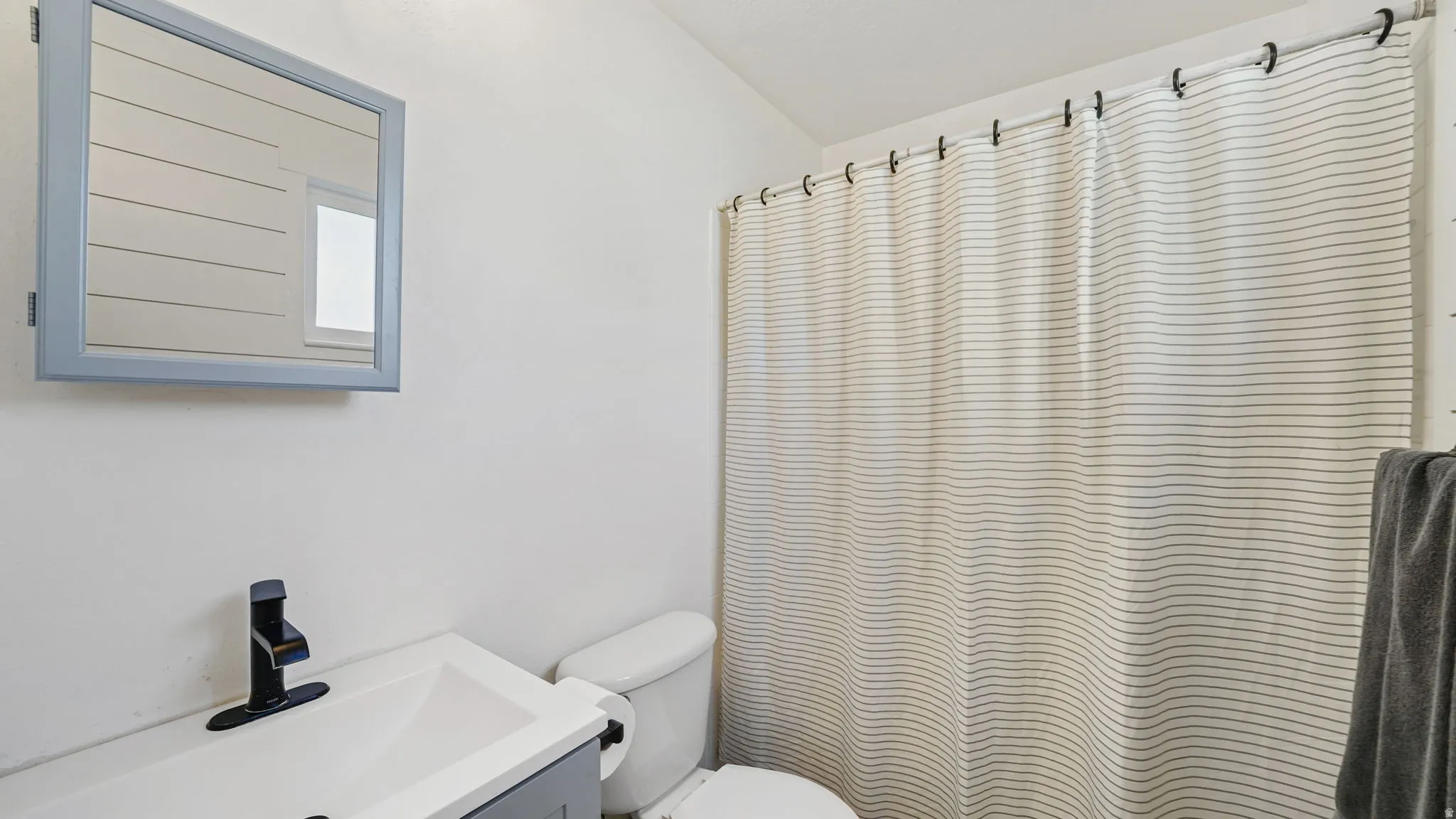 White vanity with integrated sink, black single-handle faucet, and medicine cabinet