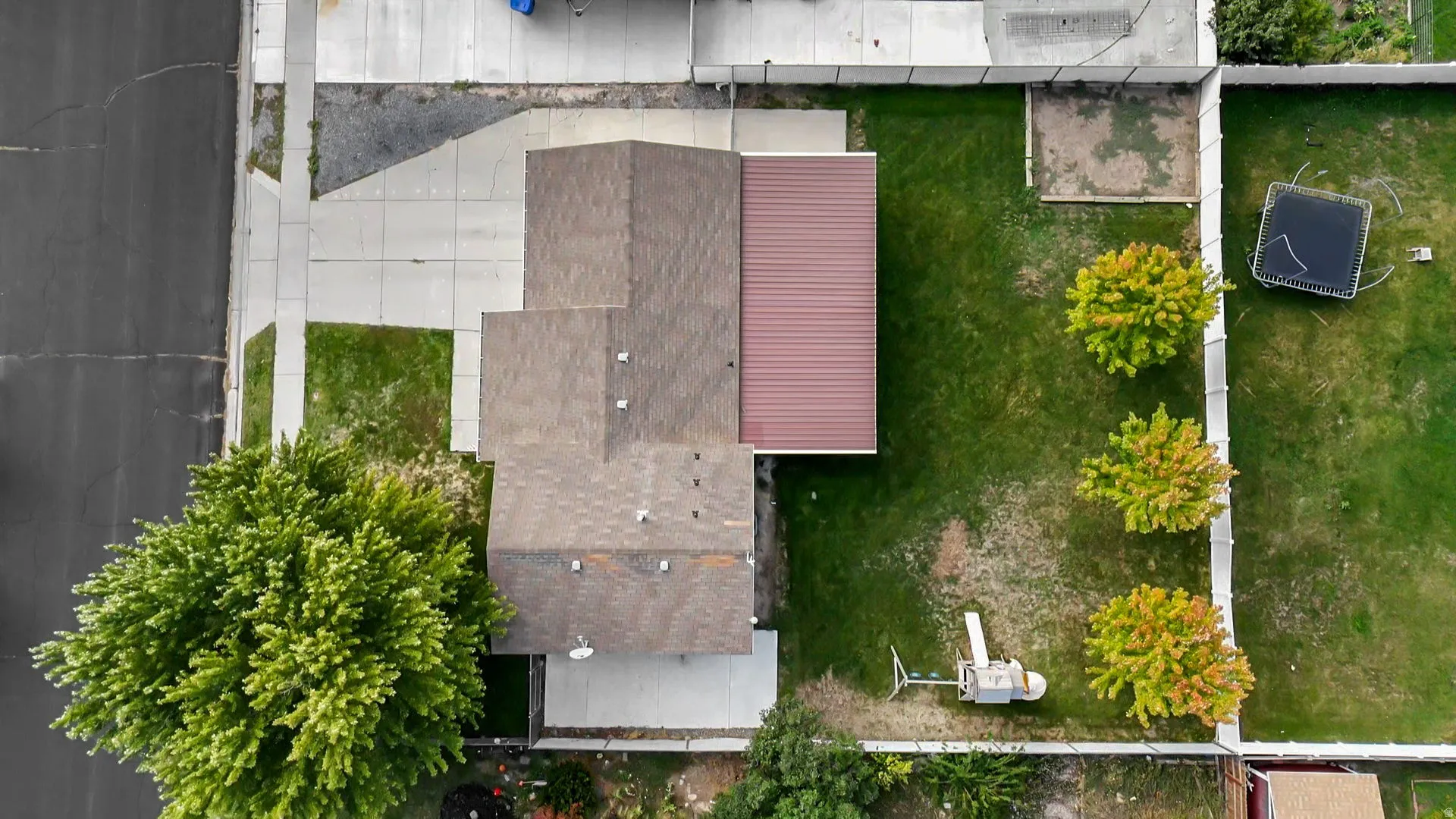 Asphalt shingle roofing, brown metal roof section, concrete driveway, concrete pathway, mature trees