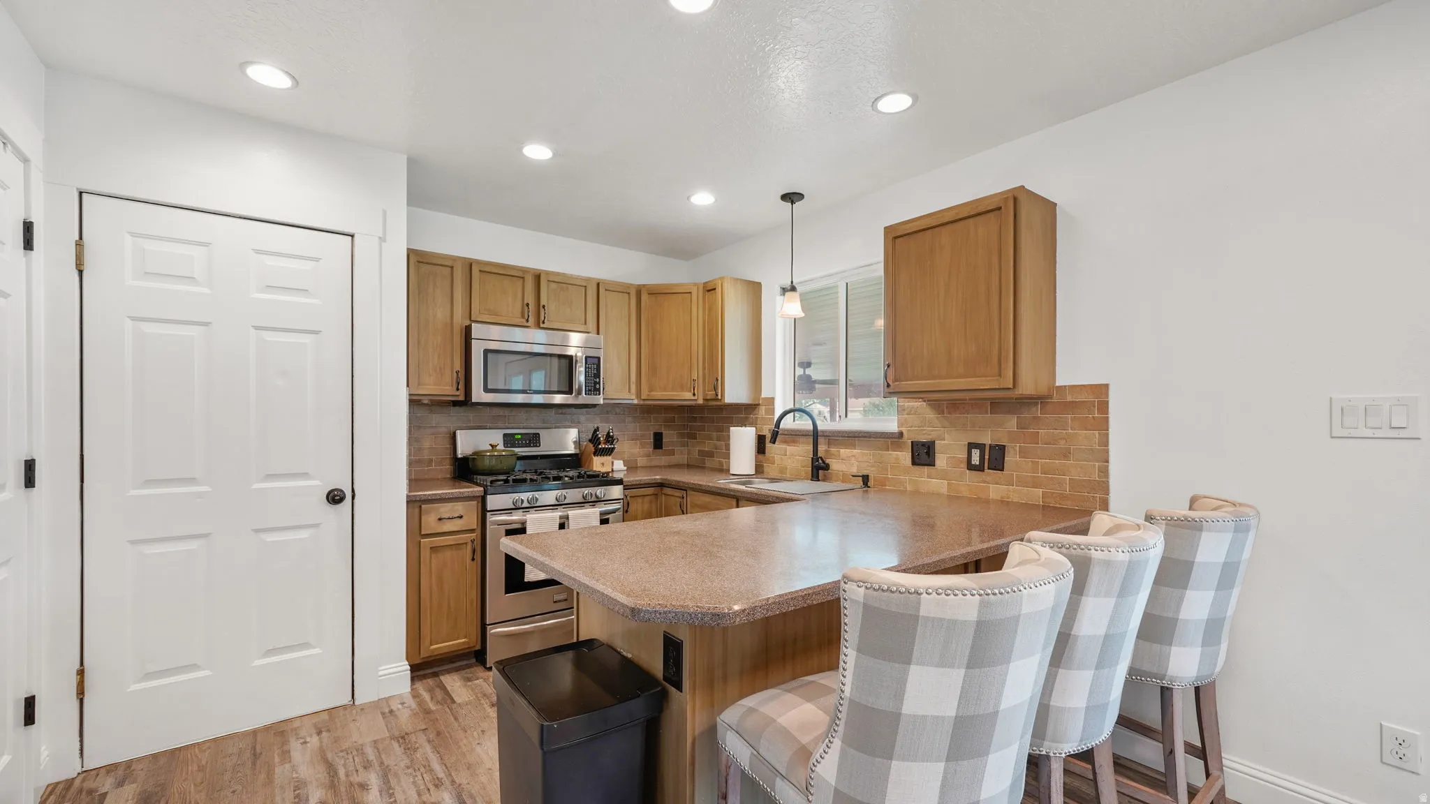 Kitchen with wood-finish flooring, recessed lighting, wood cabinetry, and stainless steel appliances
