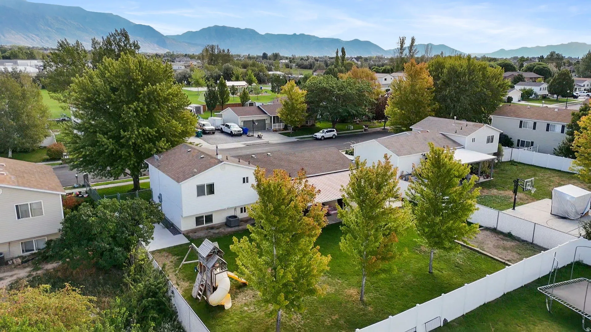 Expansive backyard featuring a covered patio, paved basketball area, and a privacy fence