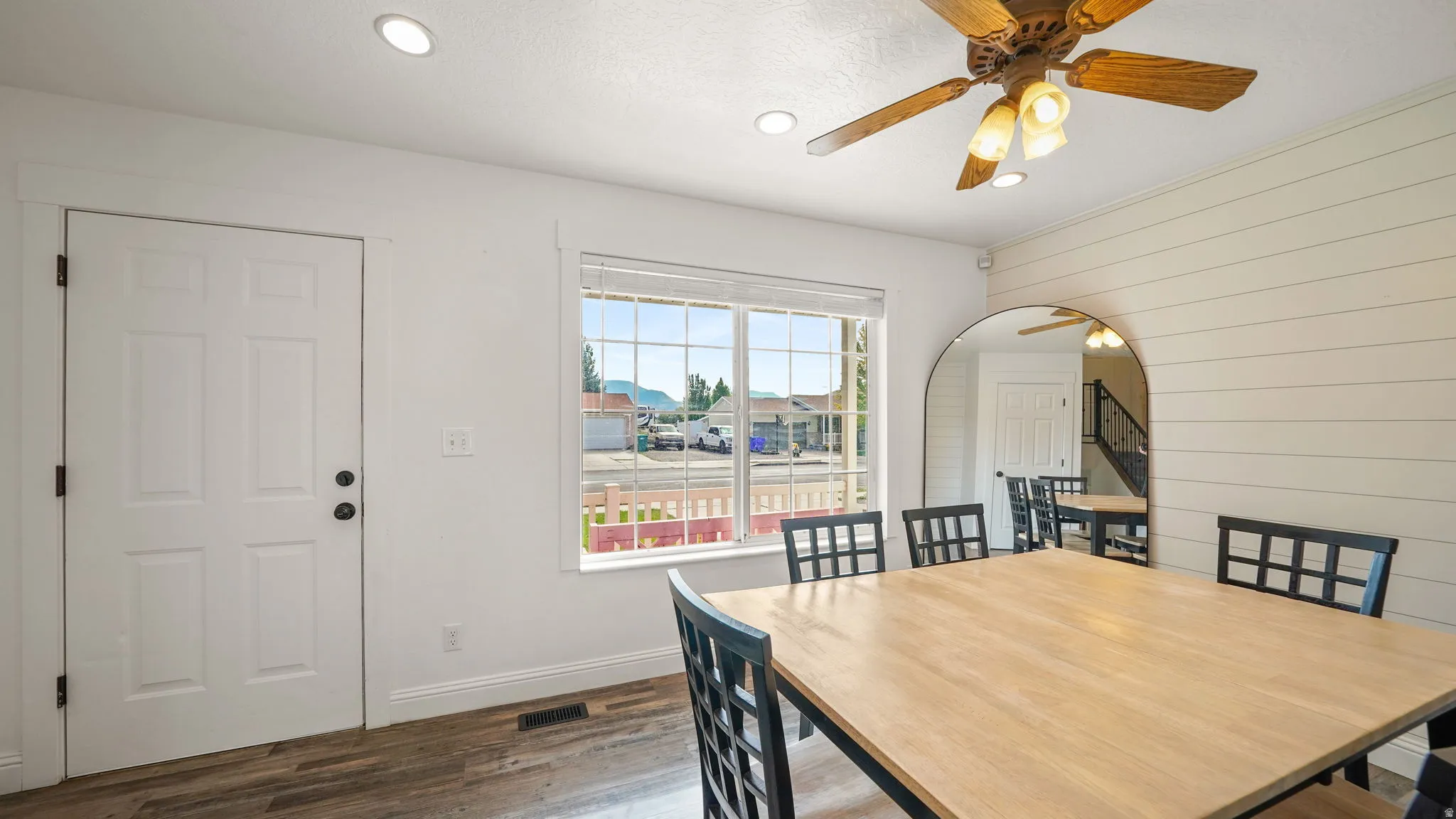 Recessed ceiling lighting, wood-finish flooring, large window, ceiling fan with integrated lighting, and shiplap accent wall