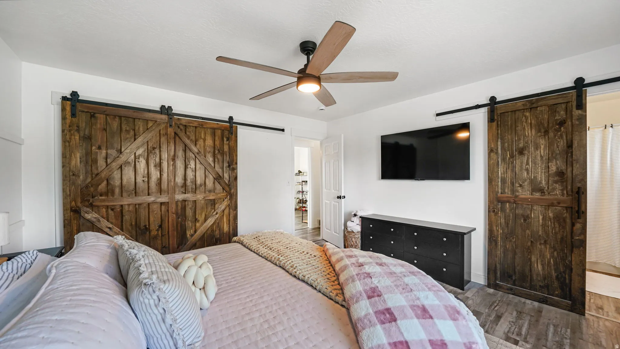 Wood-finish flooring, ceiling fan, and white walls
