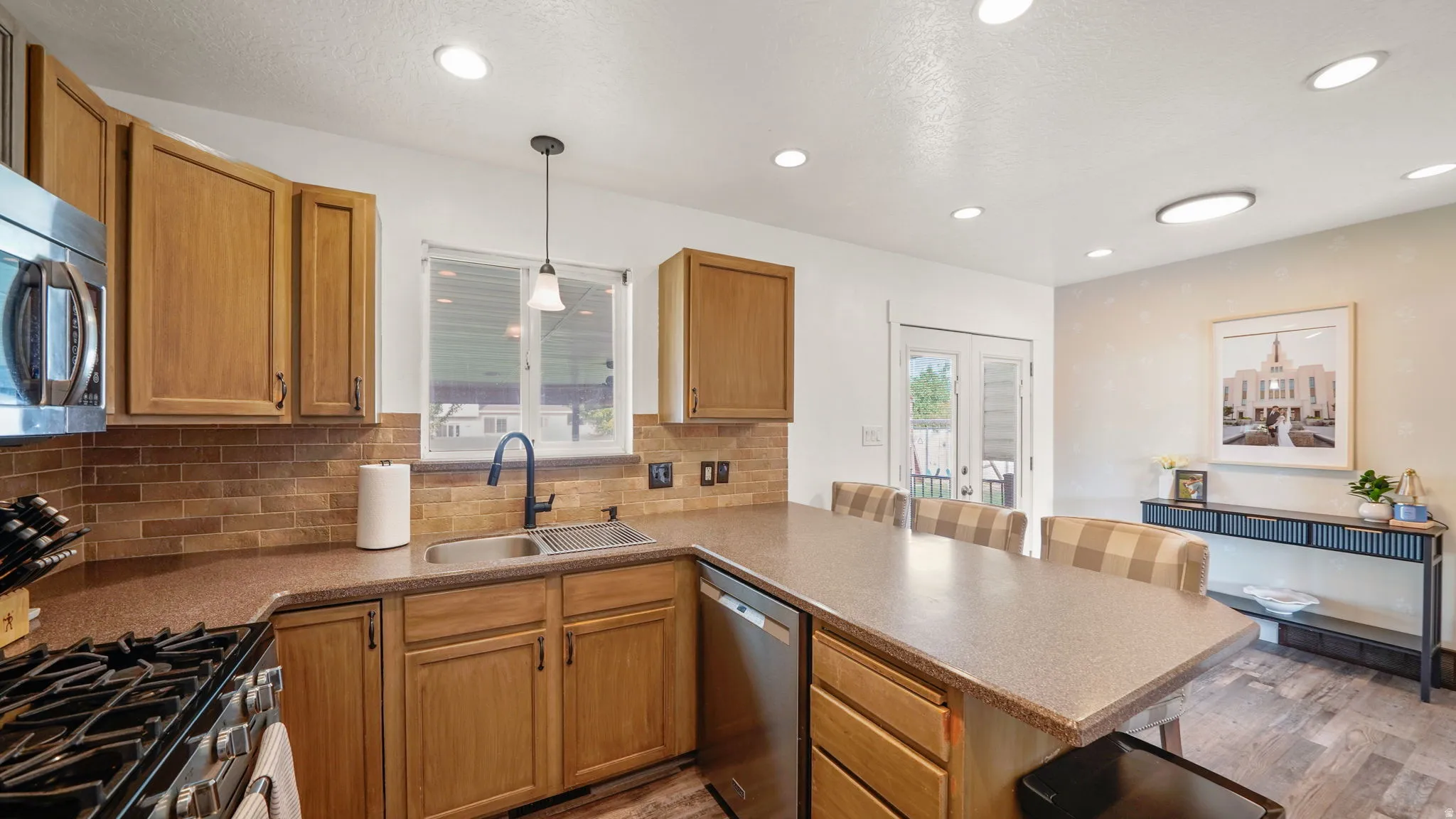 Kitchen featuring wood cabinetry, stainless steel appliances, a tile backsplash, and a double basin sink