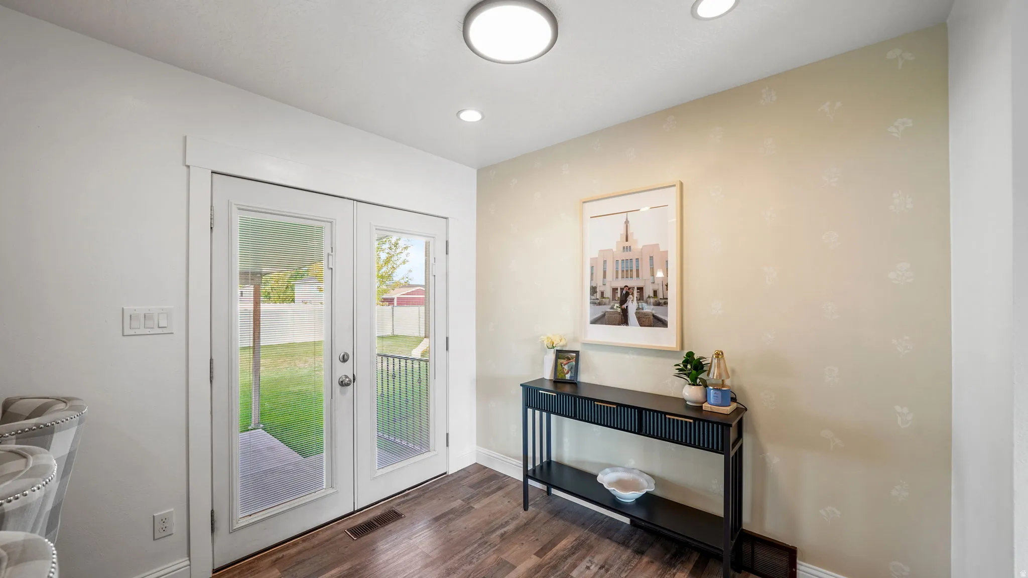 French doors with glass panels, recessed ceiling lighting, a flush mount ceiling light, wood-finish flooring, and a decorative accent wall