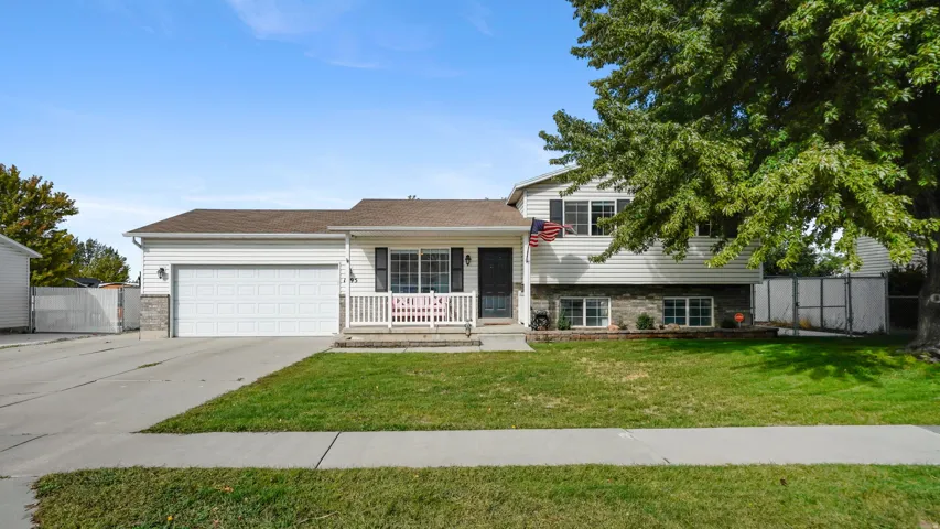 Split-level residence featuring white siding, a covered front porch, and an attached two-car garage