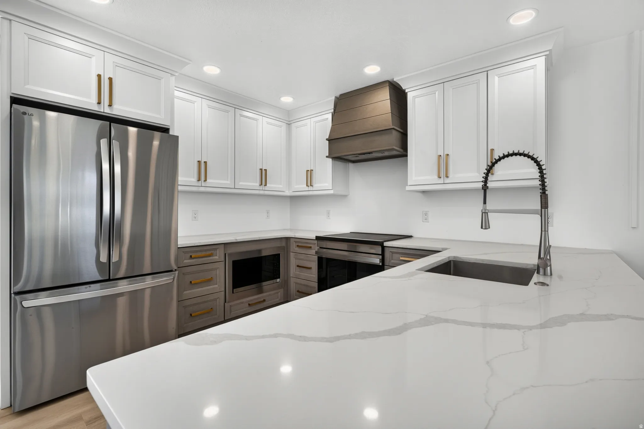 Stainless steel appliances, white shaker cabinetry, gold-finish hardware, quartz countertops, and a built-in microwave