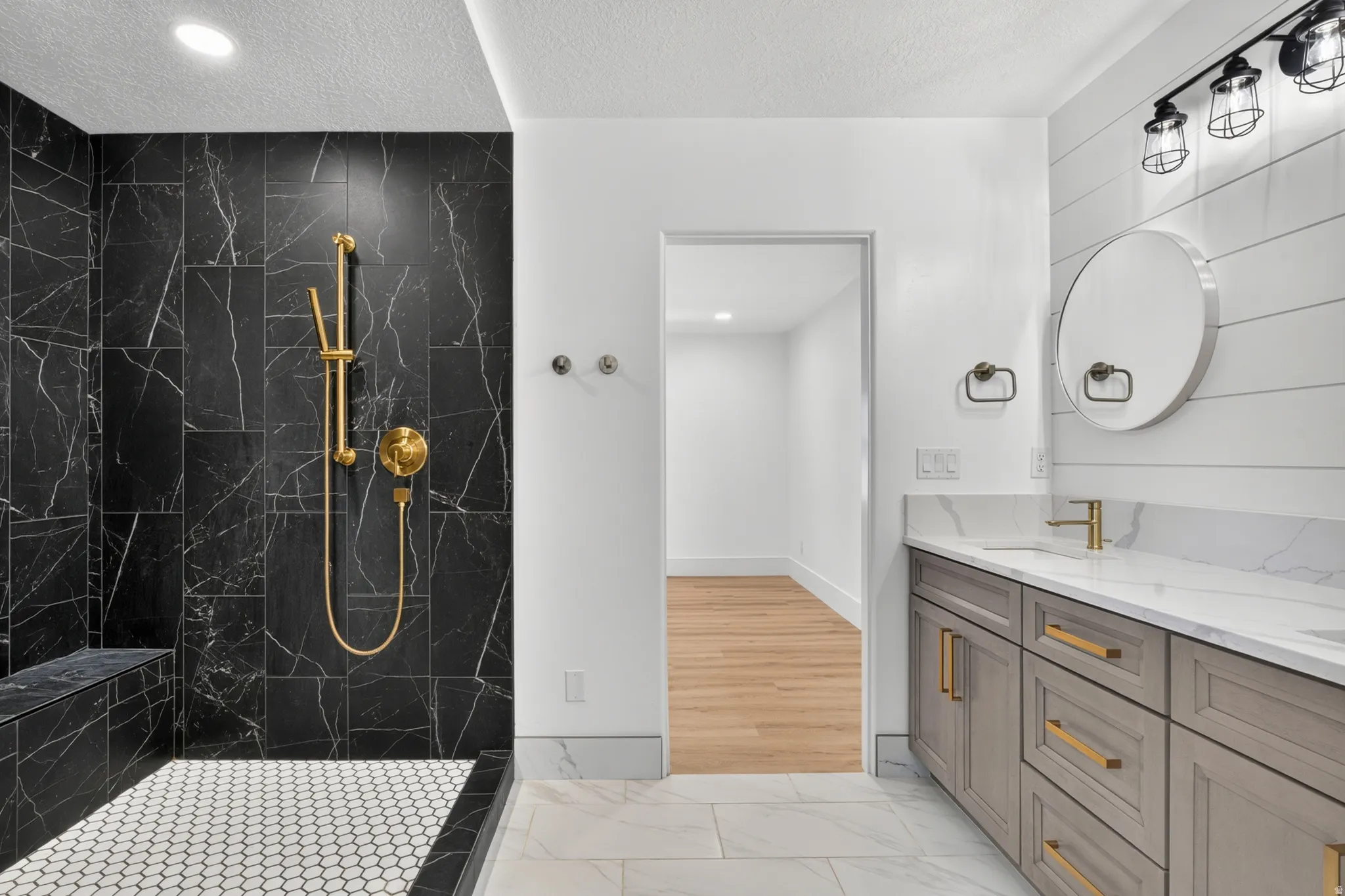Walk-in shower with black tile surround, gold-finish fixtures, and built-in bench