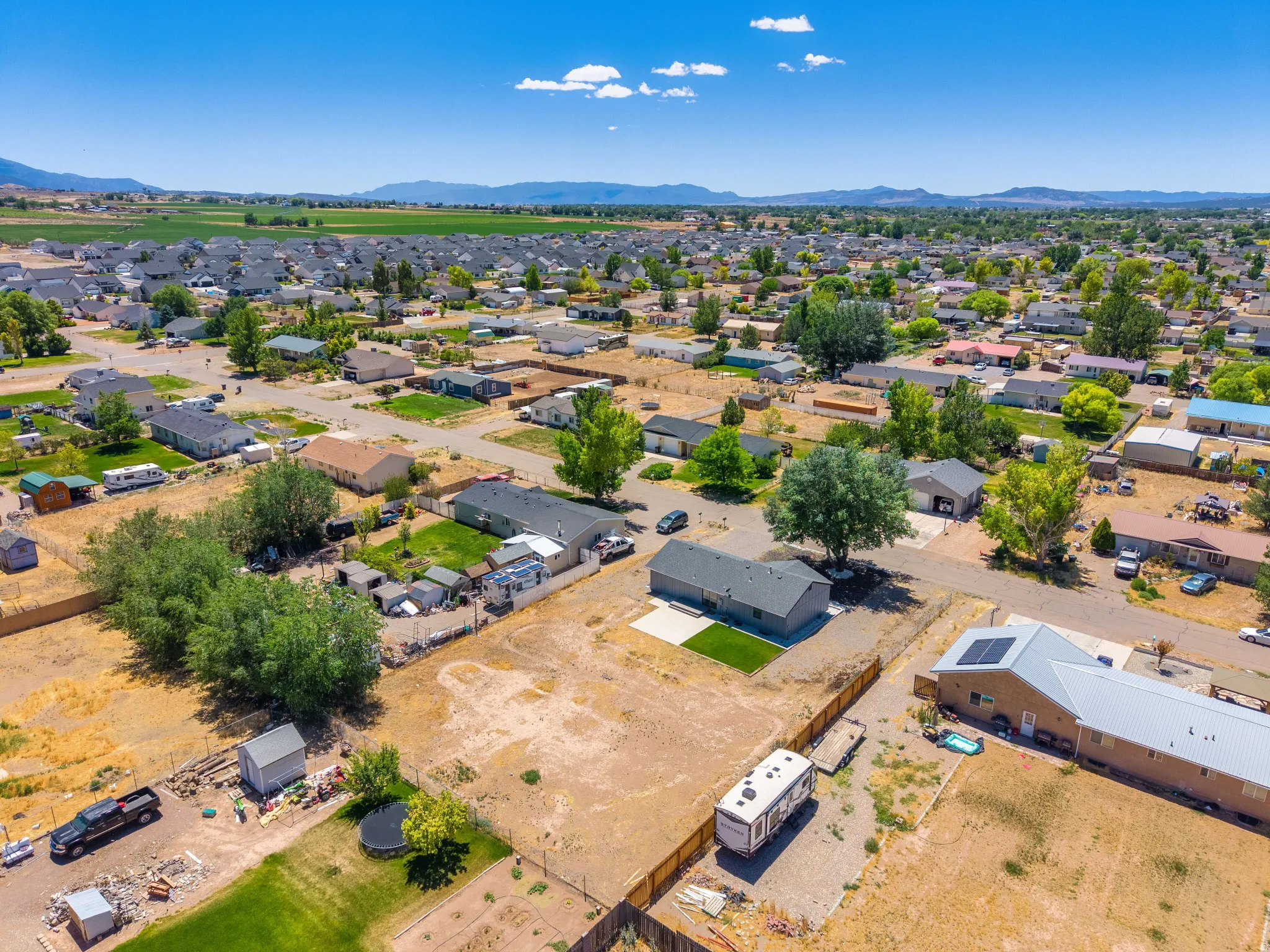 Expansive neighborhood with single-story residences, mature trees, and mountainous background