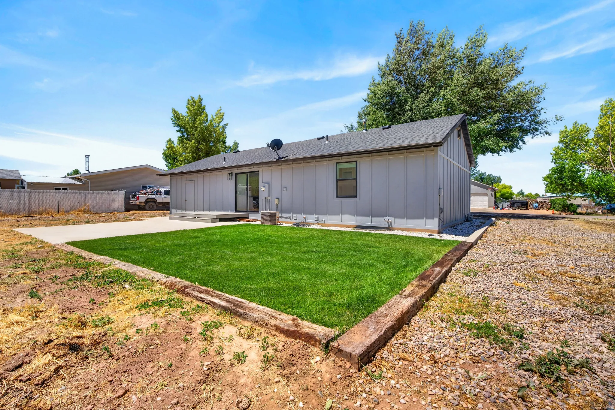 Backyard featuring a manicured lawn, concrete patio, and sliding glass door