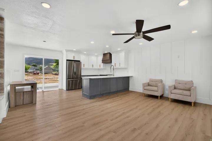 Open-concept living area with wood-finish flooring, recessed lighting, and a dark-finish ceiling fan