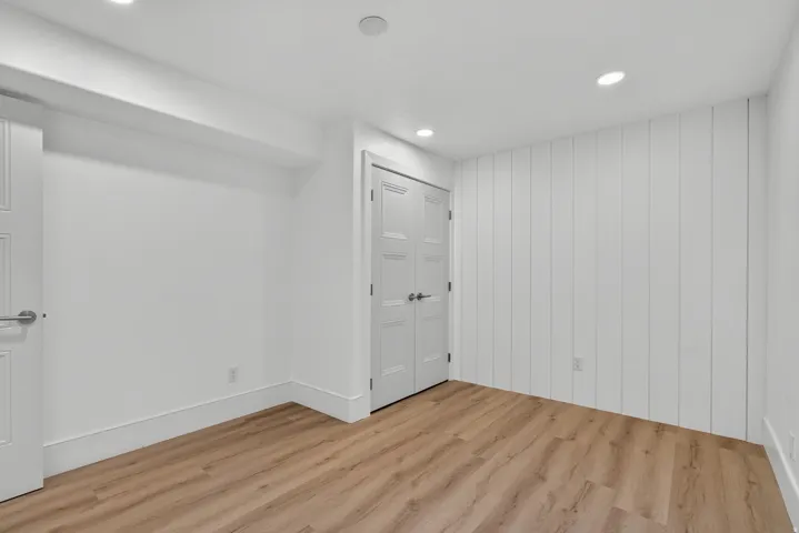 Recessed lighting, wood-finish flooring, and white paneled walls