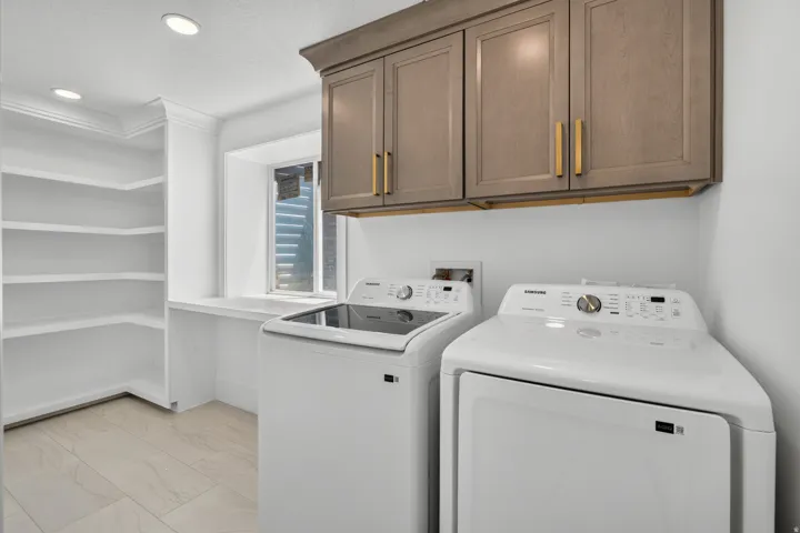 Built-in shelving, recessed lighting, upper cabinetry with gold-tone hardware, and a window provide functional elements