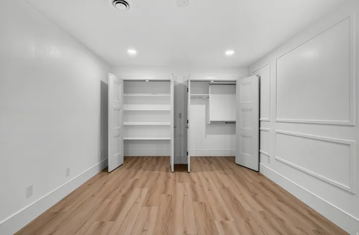 Wood-finish flooring, recessed lighting, and an accent wall with wainscoting details enhance this bright interior