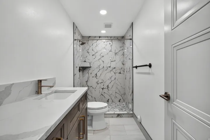 Quartz countertop vanity with wood-finish cabinetry and bronze-tone fixtures