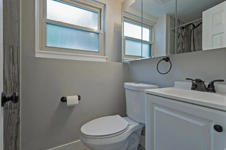 White paneled vanity with integrated sink, bronze-finish faucet, and a wall-mounted medicine cabinet