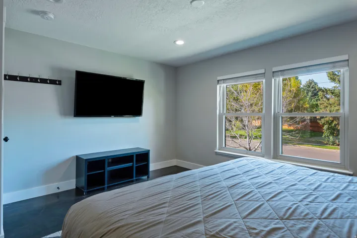 Dual windows with roller shades, recessed ceiling lighting, and dark wood-finish flooring
