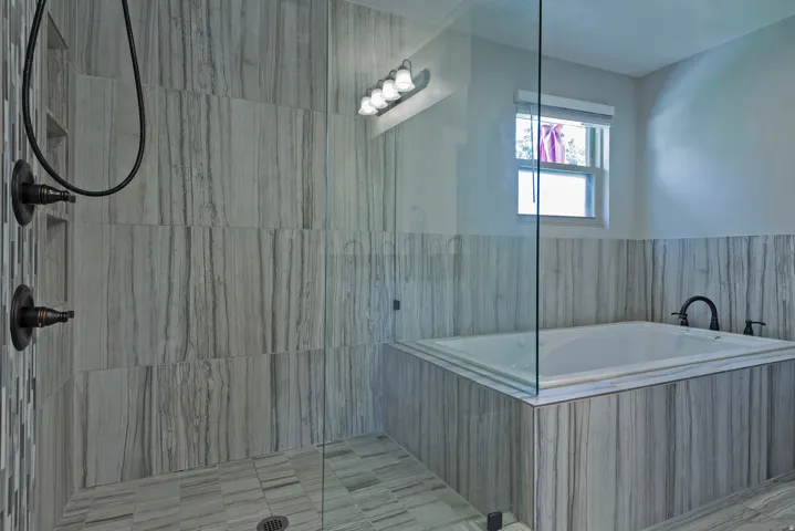 Tiled shower with dark bronze fixtures and recessed niches