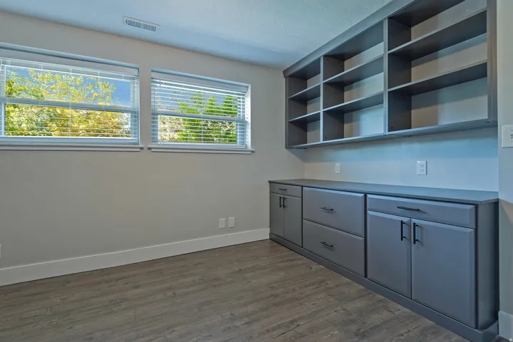 Built-in shelving and cabinetry, wood-finish flooring, and two windows with blinds