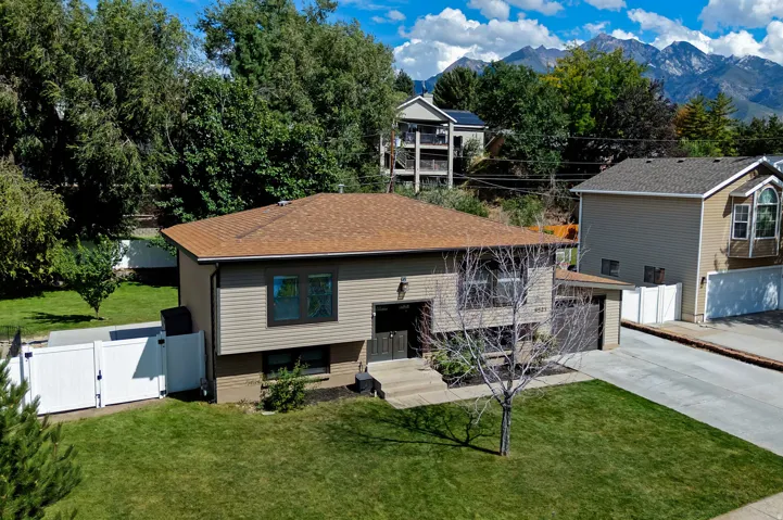 Multi-level residence featuring a shingle roof, siding facade, attached garage, and a manicured lawn