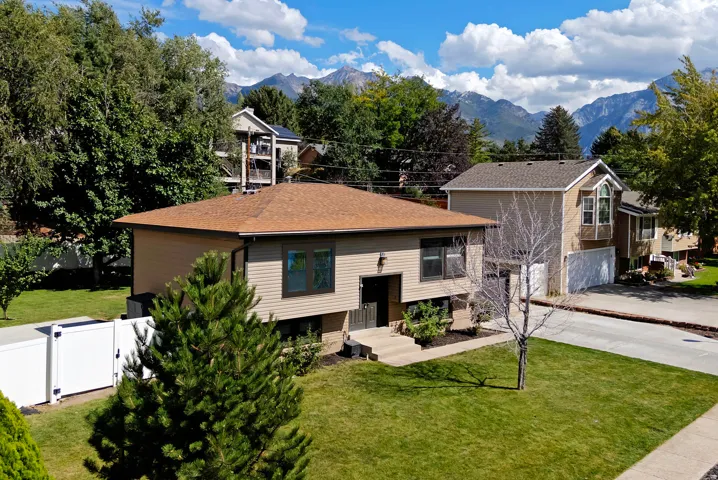 Exterior with neutral siding, brown shingle roof, and established front landscaping