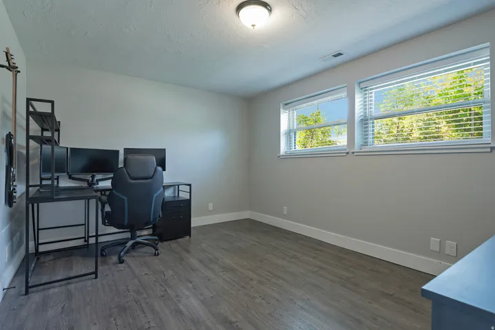 Wood-finish flooring, multiple windows with blinds, and white trim accents