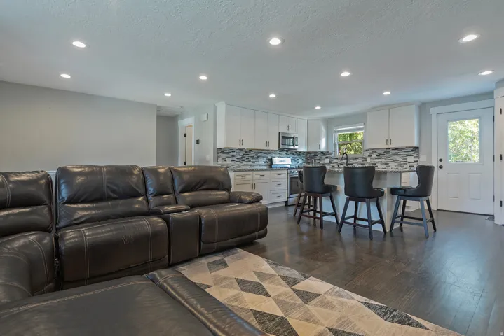 Open-concept living area featuring dark wood-finish flooring, recessed lighting, and a kitchen island with seating