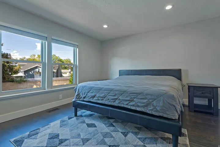 Recessed lighting, light gray walls, dark wood-finish flooring, and two large windows