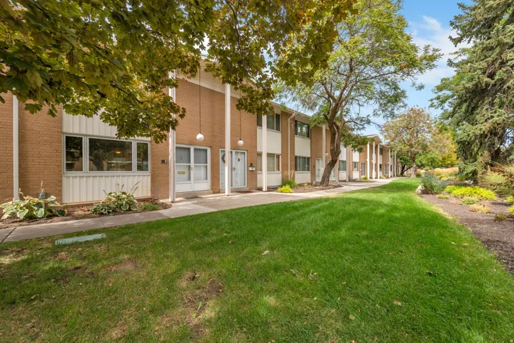 Brick exterior with expansive green space, mature trees, and established landscaping