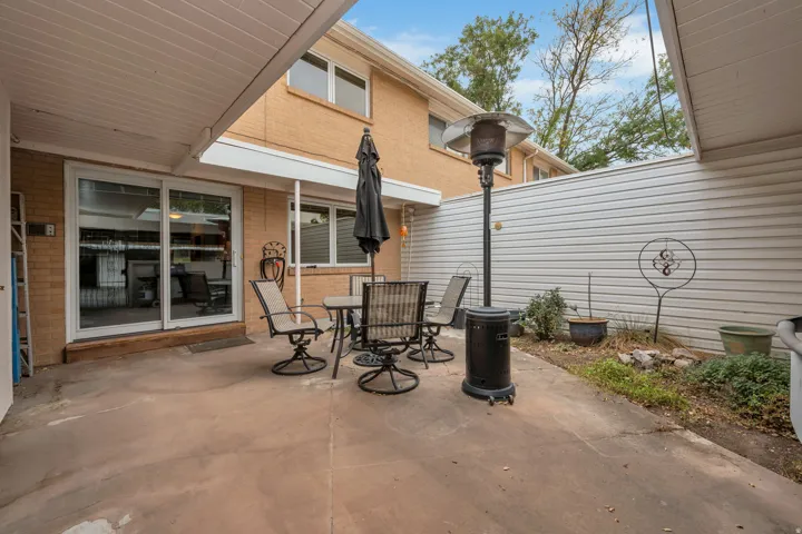 Covered concrete patio with sliding glass doors and a brick exterior