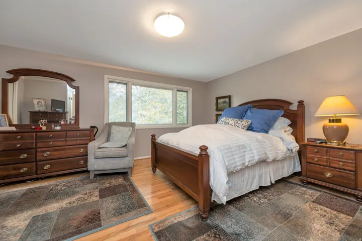 Hardwood flooring, neutral wall tones, large window, and overhead lighting