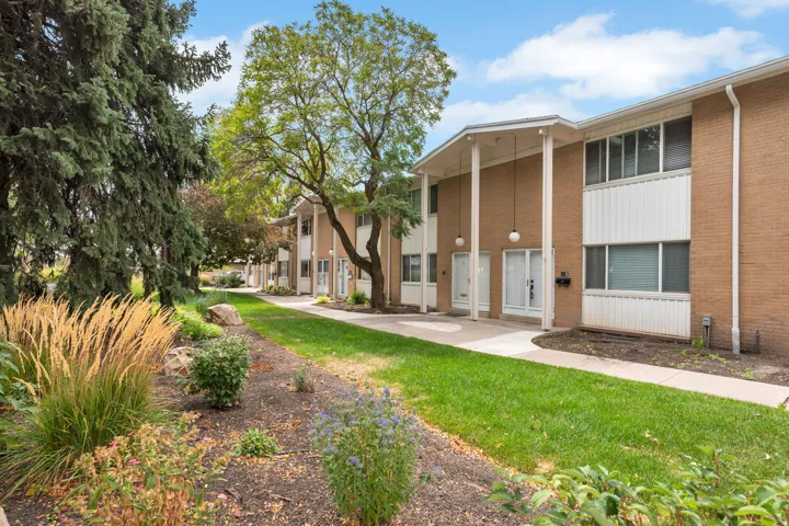 Brick exterior with white accents, mature landscaping, sidewalk access, and established trees