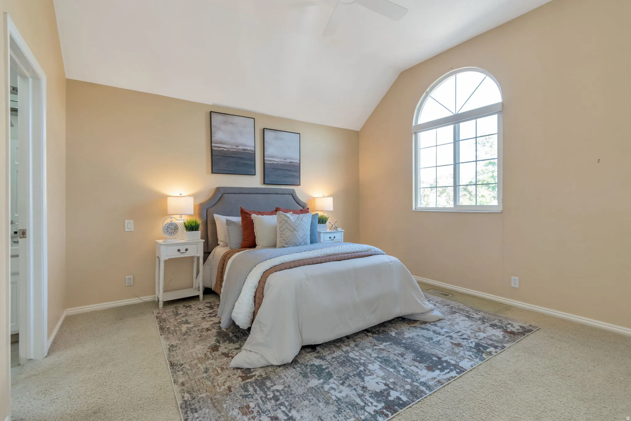 Vaulted ceiling with a ceiling fan, arched window, and carpeted flooring